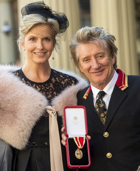 Singer Rod Stewart poses at Buckingham Palace with his wife, Penny Lancaster after receiving his knighthood, in London