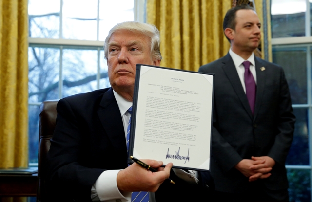Donald Trump exibe o documento que põe termo ao Mexico City Policy, assinado a 23 de janeiro de 2017. [Fotografia: Kevin Lamarque/Reuters]