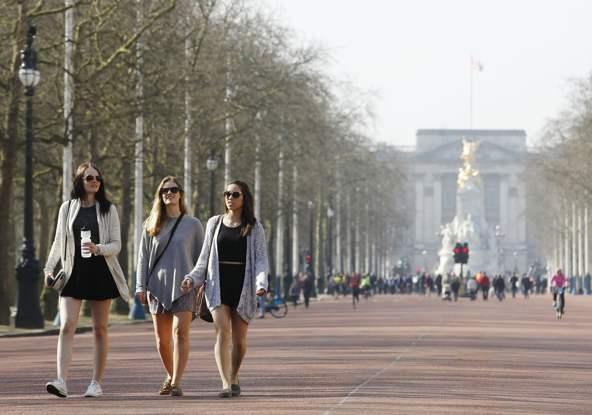 Women walk along The Mall by Buckingham Palace in the sun as the weather warms in London