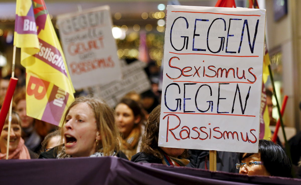 Women hold up placards during a protest in the Cologne main railways staion