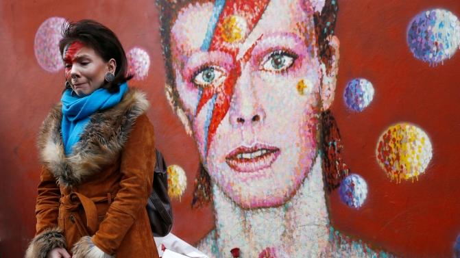 Uma mulher pintada ao estilo Ziggy Stardust chora em frente ao mural de homenagem a Bowie, em Brixton, sul de Londres (REUTERS/Stefan Wermuth)