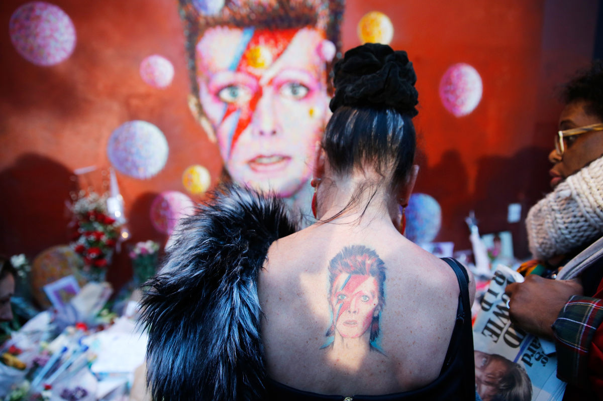 Uma mulher com uma tatuagem do Ziggy Stardust nas costas, junto ao mural a David Bowie em Brixton, sul de Londres (REUTERS/Stefan Wermuth)