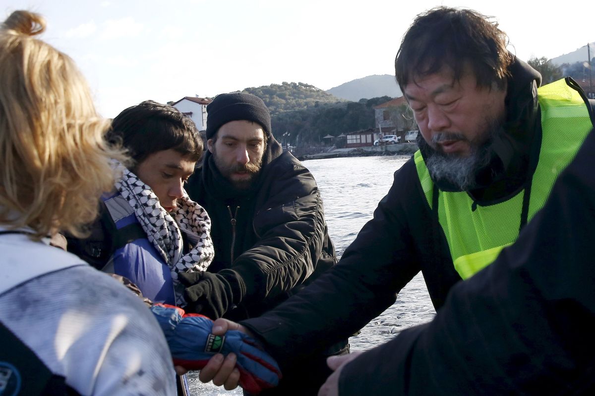 Chinese artist Ai Weiwei helps an Afghan migrant as he arrives with other refugees and migrants on a raft on the Greek island of Lesbos, file