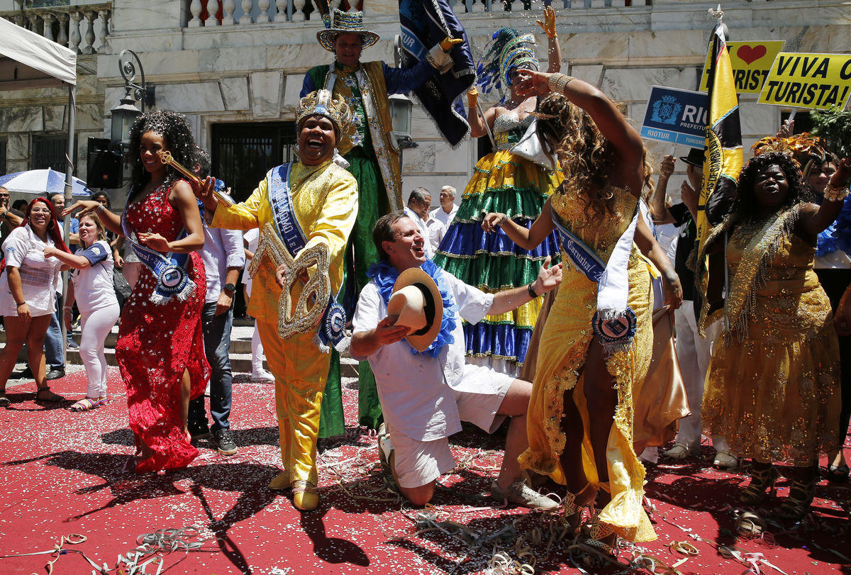 Rio de Janeiro’s Mayor Paes kneels next to the “Rei Momo”, or Carnival King Neto, as they pose during the handing over of the ceremonial key to the city at the Cidade Palace in Rio de Janeiro