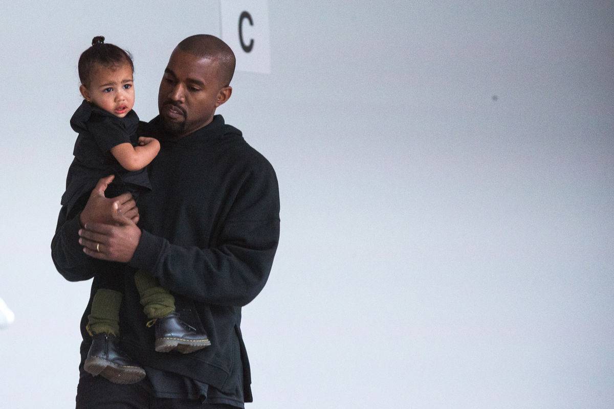 Kanye West carries his daughter, North, while preparing for a presentation of his Fall/Winter 2015 partnership with Adidas at New York Fashion Week