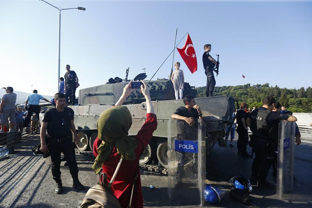 A woman takes a photo of policemen after troops involved in the coup surrendered on the Bosphorus Bridge in Istanbul