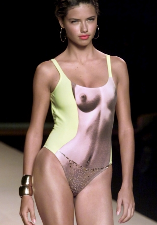 Brazilian model Adriana Lima wears a printed nude body and belly ring in lemon yellow one-piece with..