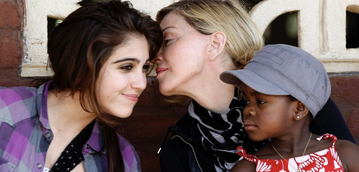 Madonna holds her adopted Malawian child James as she jokes with her biological daughter Lourdes during a visit to Gumulira village