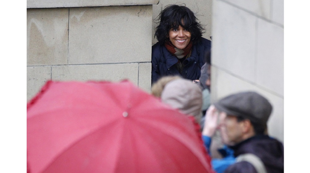 Actress Halle Berry smiles as she takes shelter from the rain during filming of “Cloud Atlas” in Glasgow, Scotland