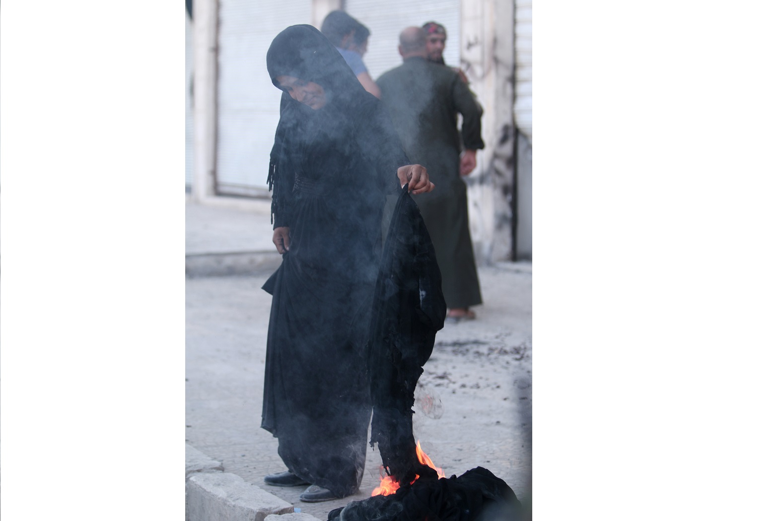 A woman sets fire to a niqab after she was evacuated with others by the Syria Democratic Forces (SDF) fighters from an Islamic State-controlled neighbourhood of Manbij