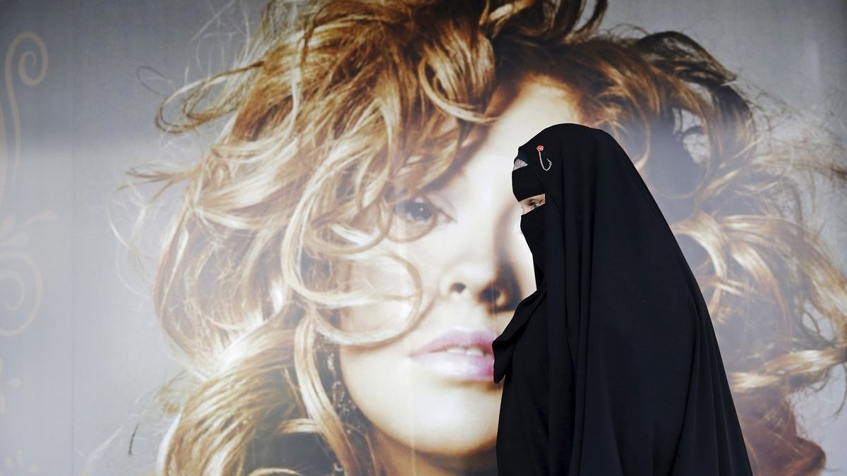 Gisele Marie, a Muslim woman and professional heavy metal musician, walks past a poster after a rehearsal at her house, in Sao Paulo