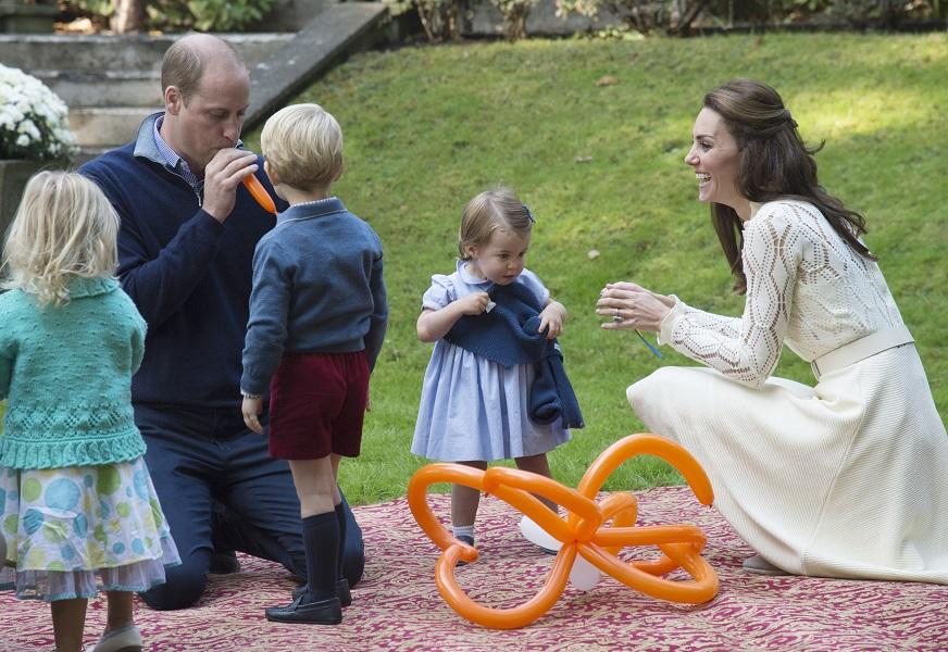 Prince George watches as his father the Duke of Cambridge blows up a balloon for him with the Duchess of Cambridge and Princess Charlotte during a children’s party Government House in Victoria
