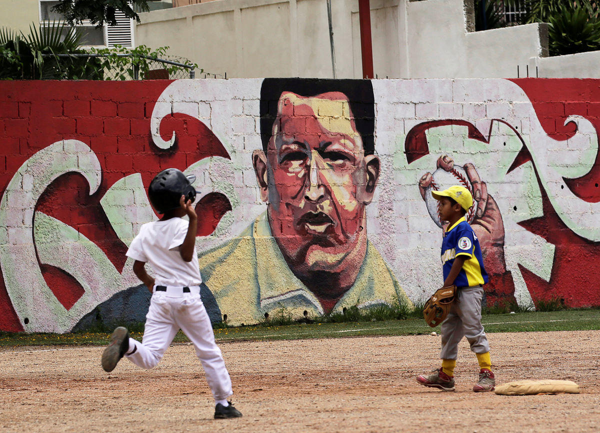 Children play baseball near a mural of Venezuela’s late president Hugo Chavez, in Caracas, Venezuela