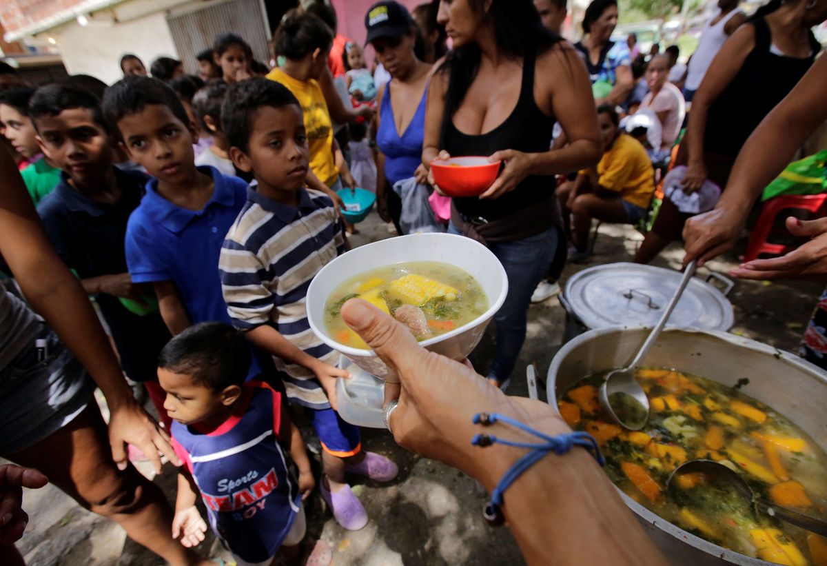 Children queue wait to receive free food which was prepared by residents and volunteers on a street in the low-income neighborhood of Caucaguita in Caracas