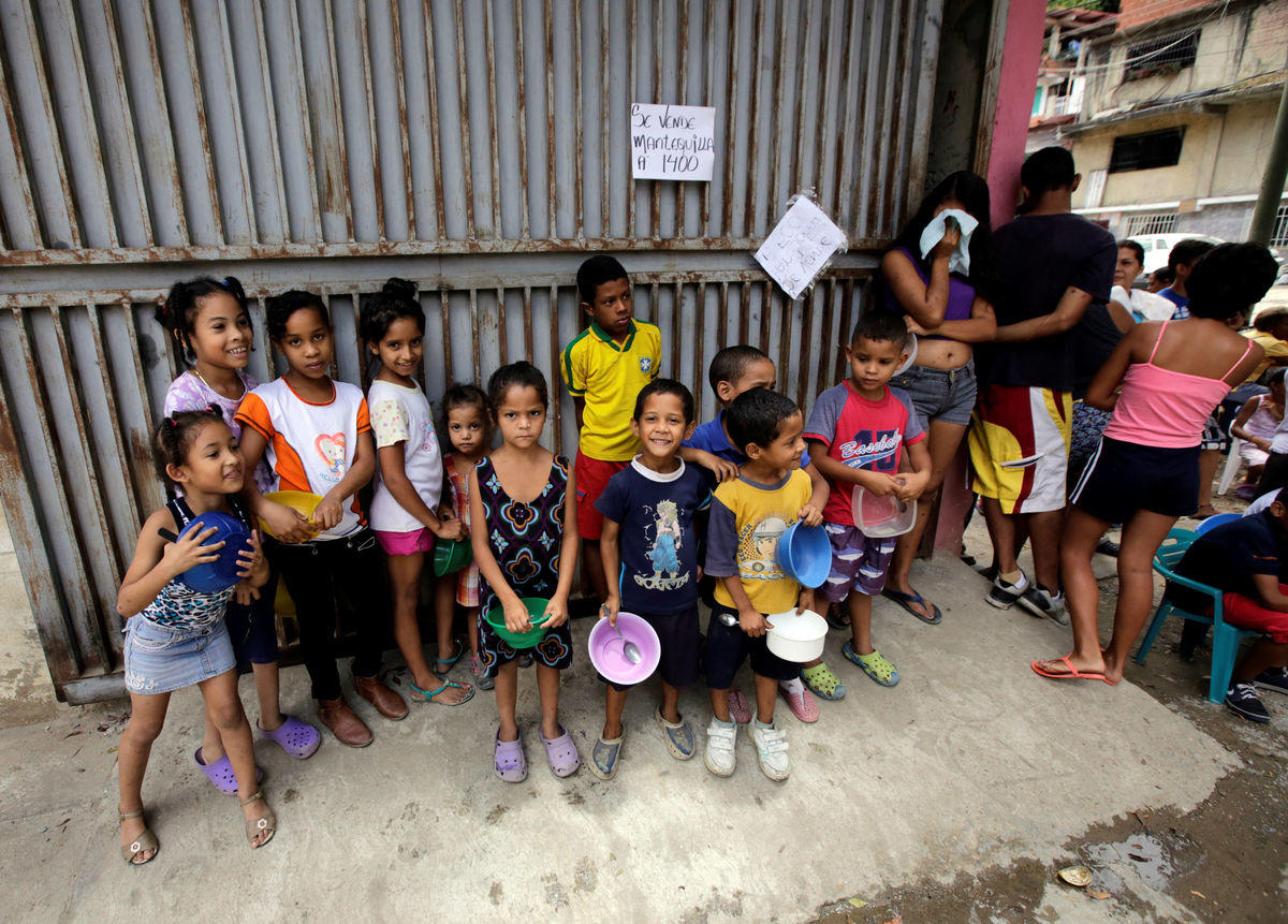 Children and people wait to receive free food which was prepared by residents and volunteers on a street in the low-income neighborhood of Caucaguita in Caracas