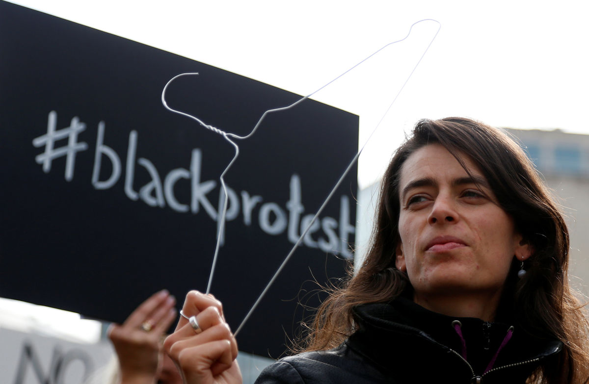 A demonstrator holds up a hanger to protest  against a proposed parliament bill to completely ban abortion in Poland, in front of EU institutions in Brussels