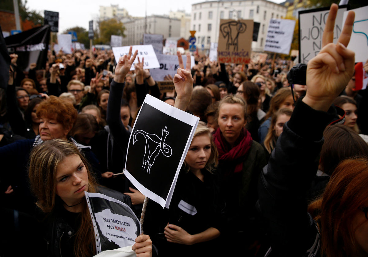 Women gesture as people gather in an abortion rights campaigners’ demonstration to protest against plans for a total ban on abortion in front of the ruling party Law and Justice (PiS) headquarters in Warsaw