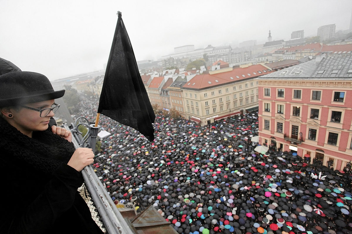 A woman observes thousands of people during an abortion rights campaigners’ demonstration to protest against plans for a total ban on abortion in front of the Royal Castle in Warsaw