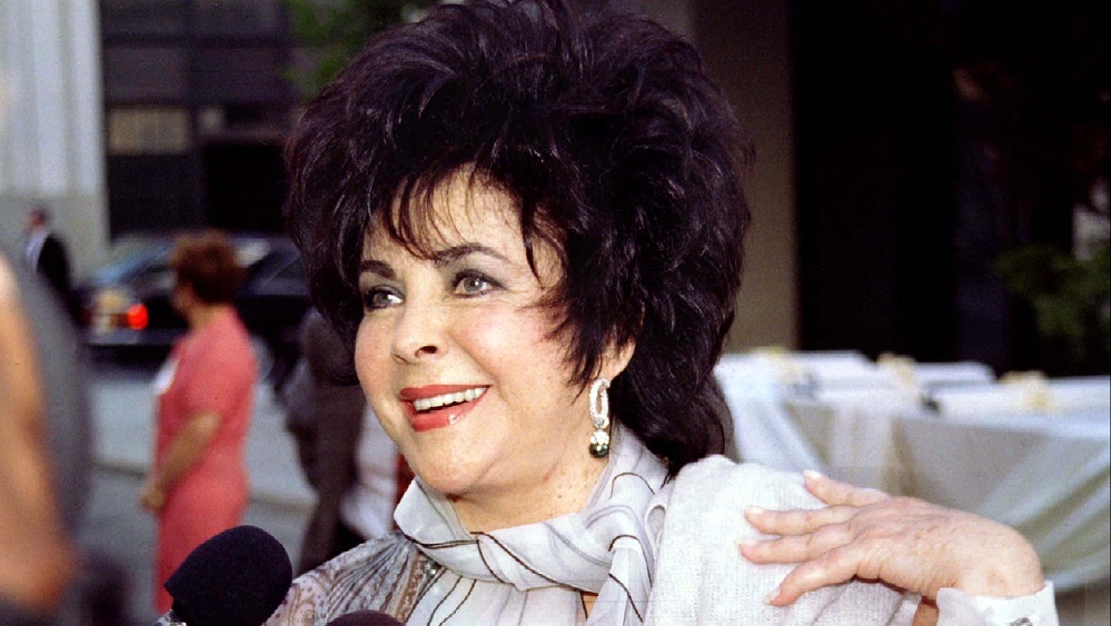 Actress Elizabeth Taylor answers reporters questions as she arrives for the opening of the Warner Br..