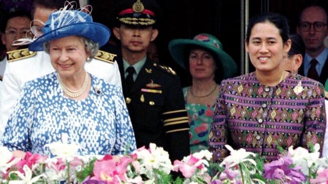 Britain’s Queen Elizabeth II (L), and Thailand’s Princess Sirindhorn (R) smile at cheering students ..