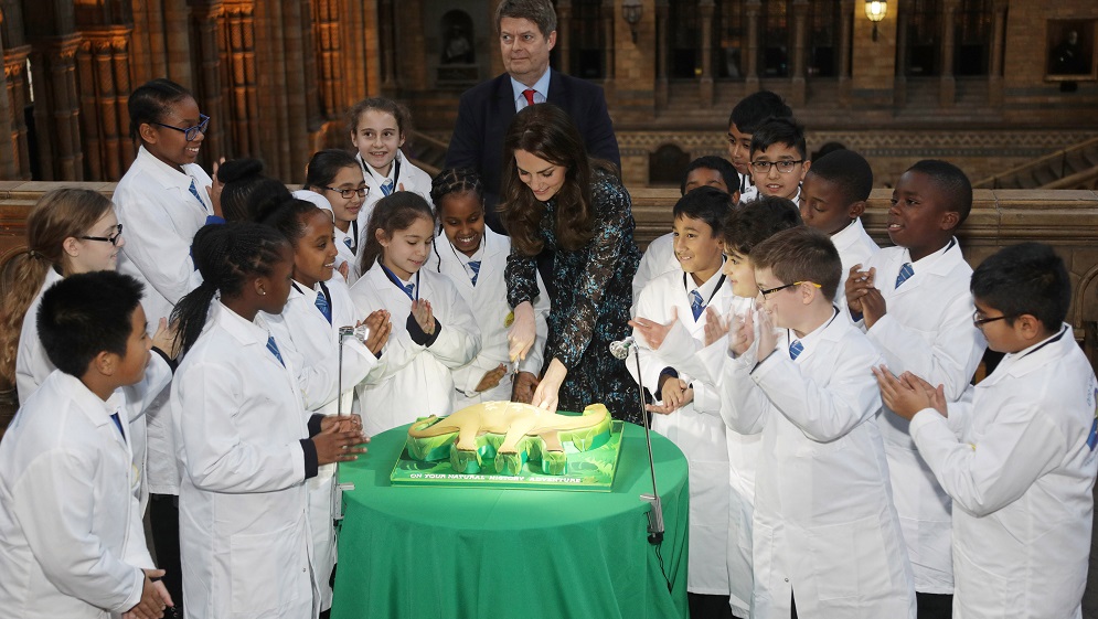 Britain’s Catherine, Duchess of Cambridge cuts a cake with pupils from Oakington Manor Primary School, as she attends a children’s tea party at the Natural History Museum in London