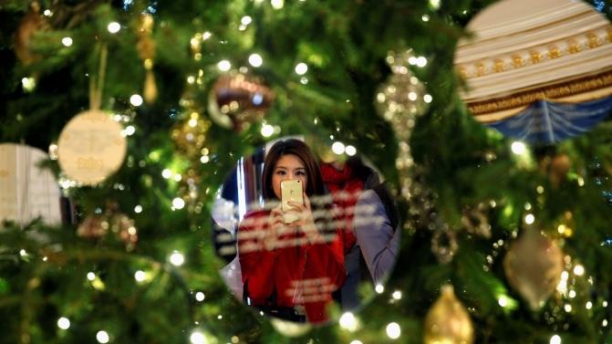 Reflected in an ornament, a reporter takes a photo of the White House Christmas Tree in the Blue Room during a media preview of the holiday decor at the White House in Washington