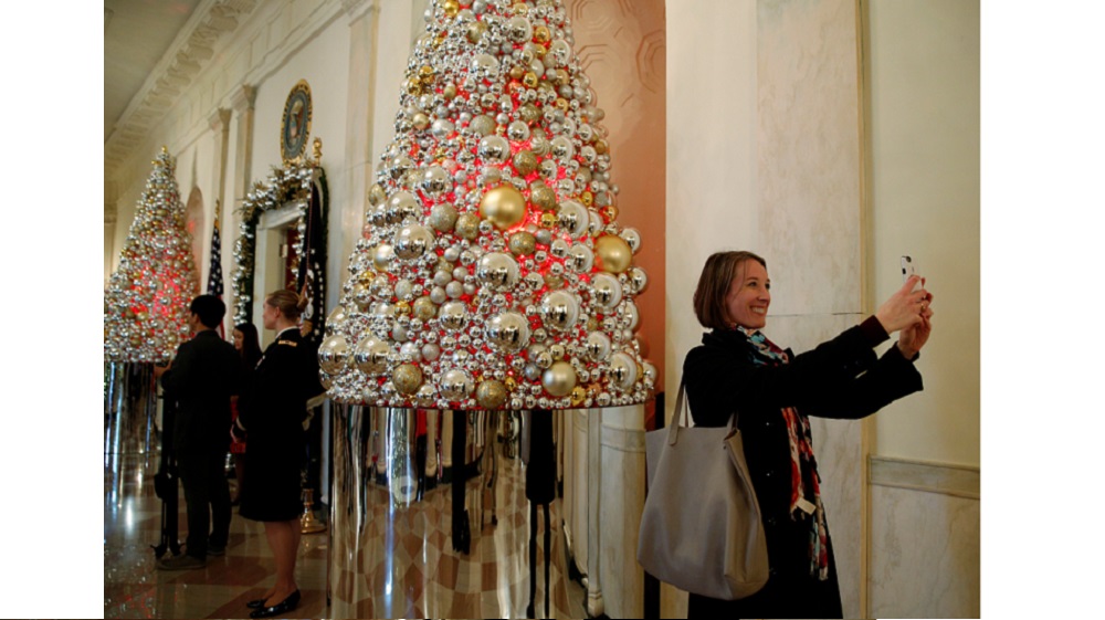 A woman takes a photo in the Cross Hall during a holiday decor preview of the White House in Washington