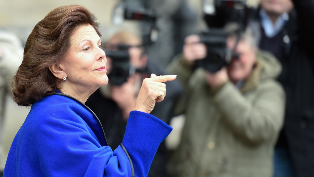 Queen Silvia of Sweden gestures to spectators after her arrival at the townhall in Hamburg