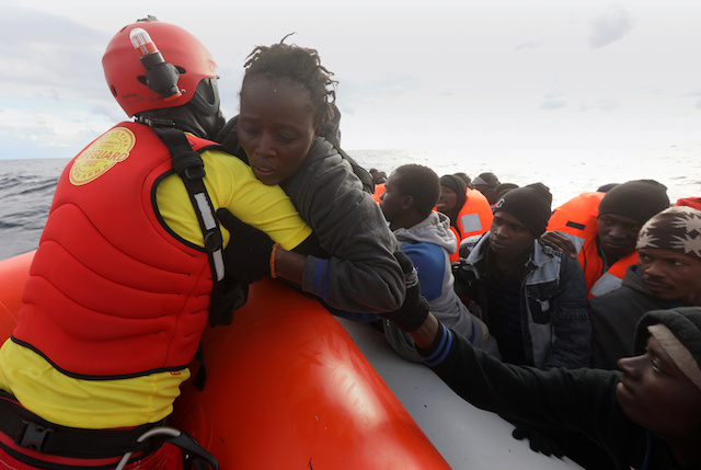 A lifeguard pulls a migrant woman to a rescue craft  from an overcrowded raft, as lifeguards from the Spanish NGO Proactiva Open Arms rescue all 112 on aboard