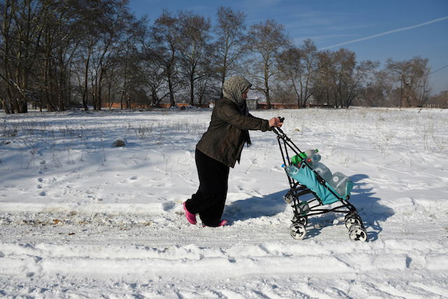 A refugee pushes a baby cart full with goods on snow at the refugee camp of the village of Vagiohori