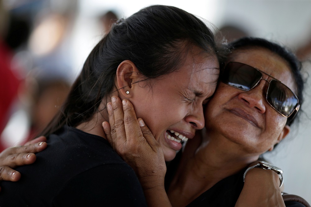 A woman is seen crying after receiving the information that her brother was one of the inmates who died during a prison riot, in front of the Medical Legal Institute in Manaus