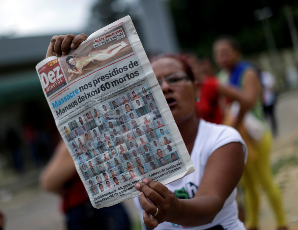 A relative of a prisoner holds a local newspaper, which frontpage shows a headline about a deadly prison riot, in front of Anisio Jobim prison in Manaus
