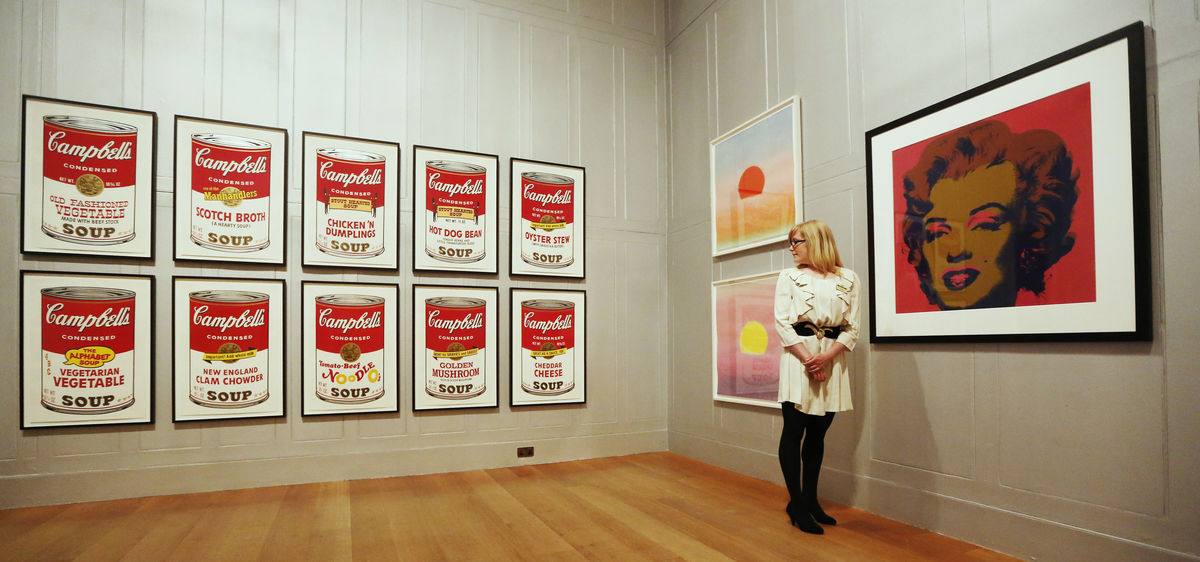 Gallery employee Maddy Adeane poses with Andy Warhol’s “Campbell’s Soup II” (1969), “Sunset” (1972) and “Marilyn” (1967) at the Dulwich Picture Gallery in London
