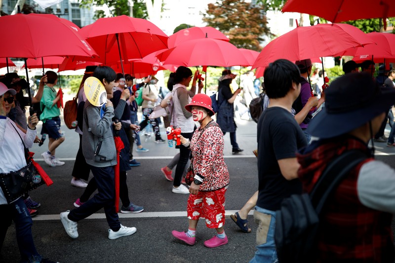 Workers from the Korean Confederation of Trade Unions (KCTU) holding red-colored umbrellas march during a May Day rally in Seoul