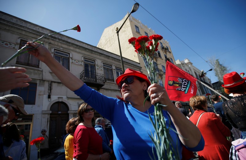 A woman distributes carnations during a May Day demonstration in Lisbon