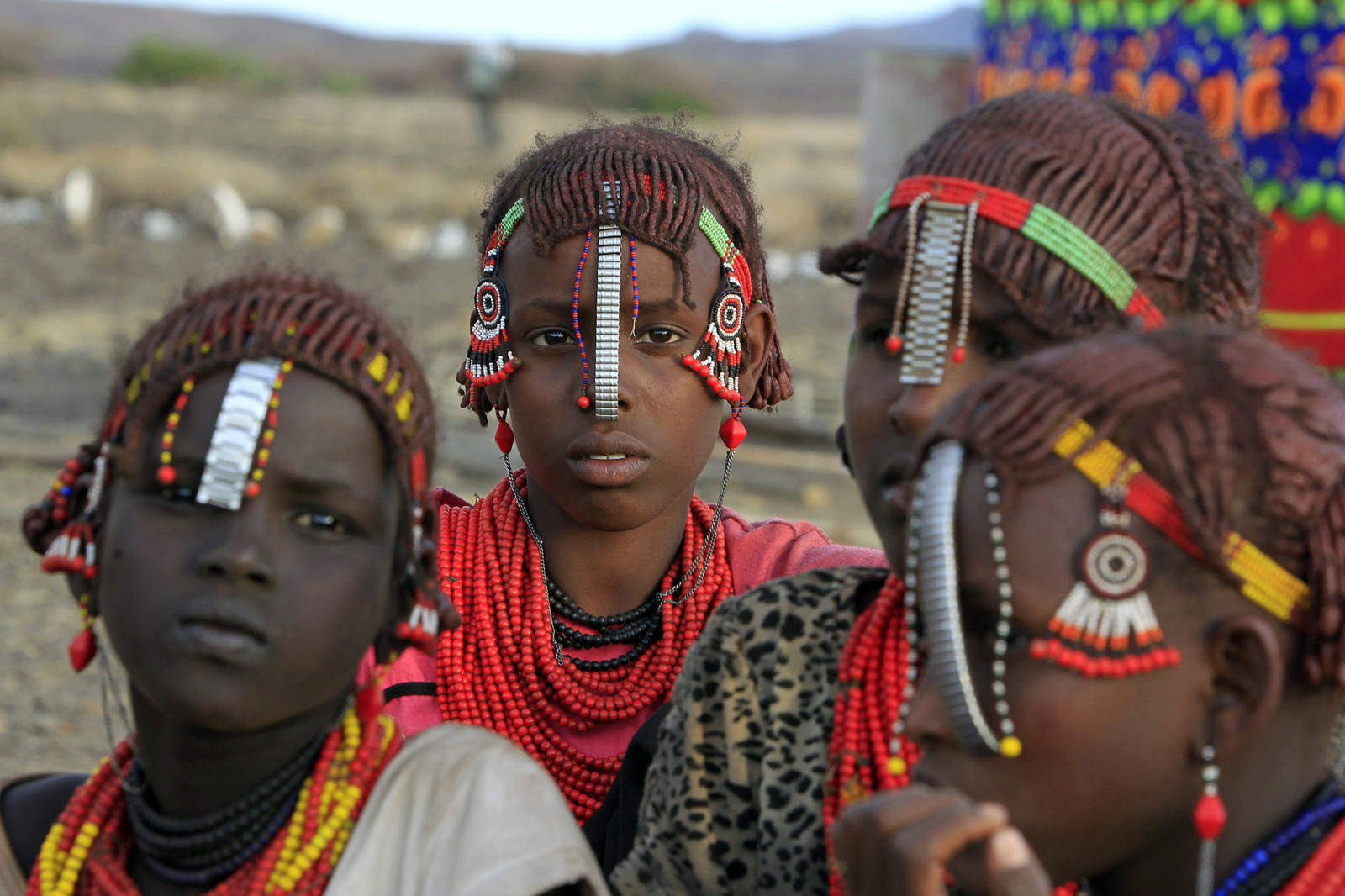 Girls from Daasanach tribe sit outside their hut at venue of a welcoming ceremony for tourists ahead of hybrid solar eclipse expected to take place on Sunday, at Sibiloi National Park on shores of Lake Turkana