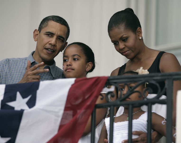 President Barack Obama talks to first lady Michelle Obama and their daughters Malia and Sasha