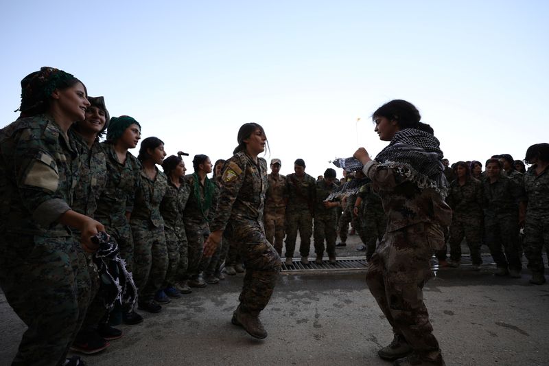 Syrian Democratic Forces female fighters dance during a graduation ceremony in the city of Hasaka