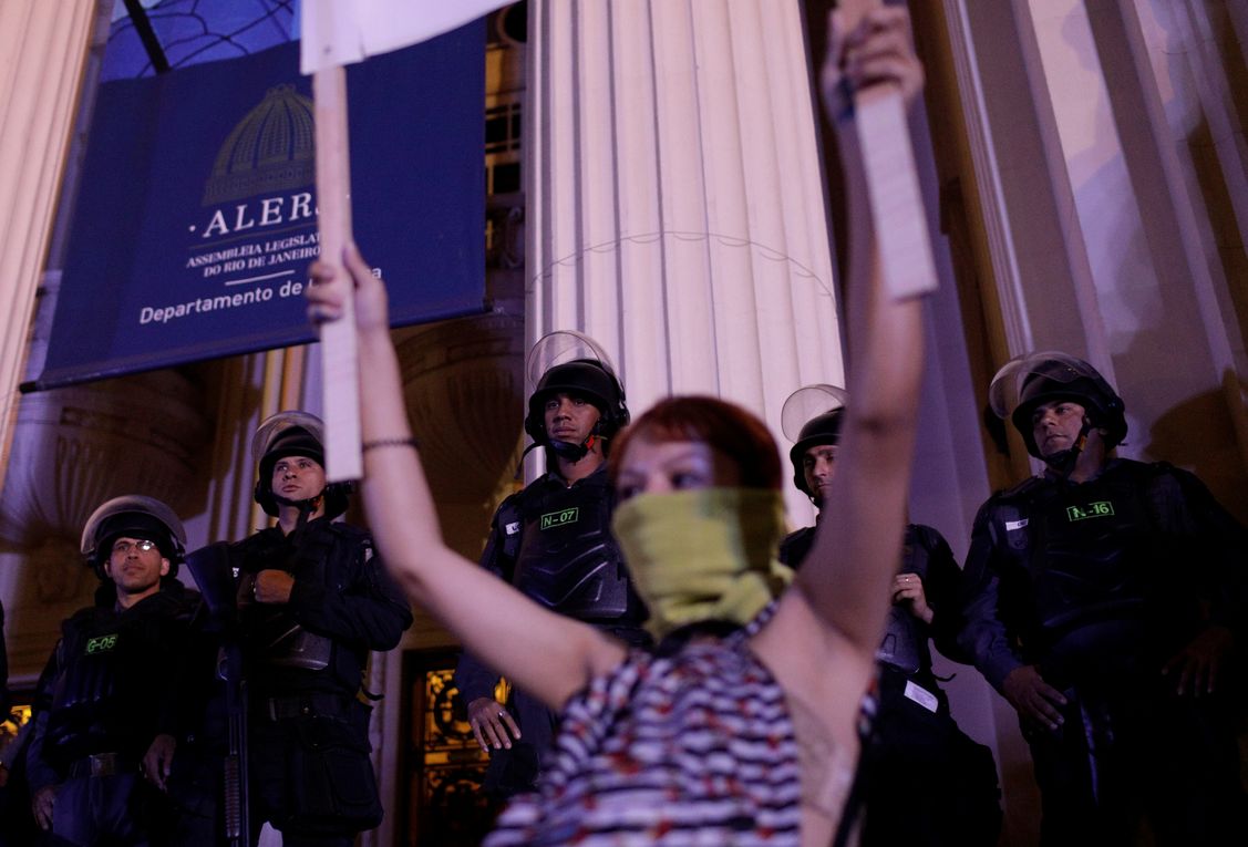 Riot policemen observe as protesters demonstrate against Brazil’s congressional move to criminalize all cases of abortion, including cases of rape and where the mother’s life is in danger, in Rio de Janeiro