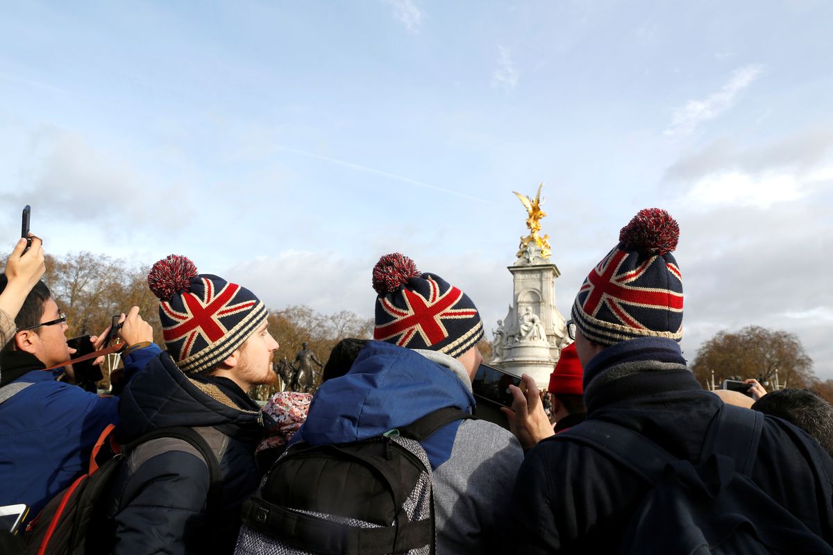 Tourists take pictures outside Buckingham Palace after Prince Harry announced his engagement to Meghan Markle, in London