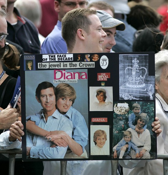 A man holds a banner with the official engagement portrait of Britain’s Prince Charles and Princess ..