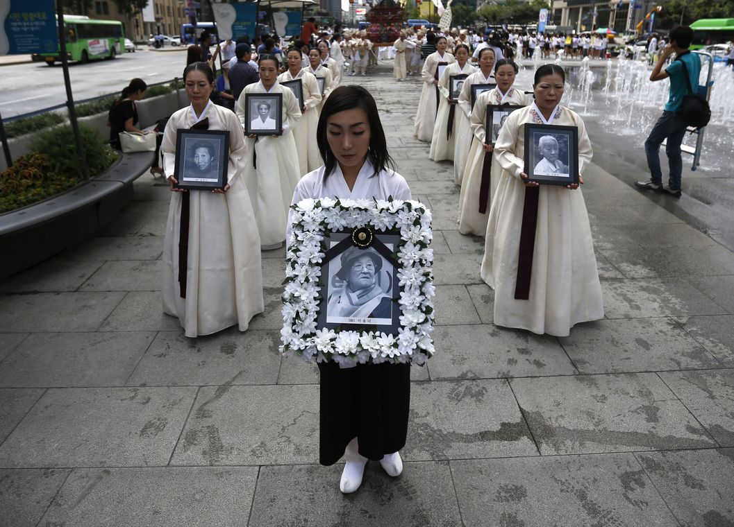 Participants carry the portraits of Korean women who were made sex slaves by the Japanese military during World War II, during a requiem ceremony for former comfort woman Lee Yong-nyeo in central Seoul