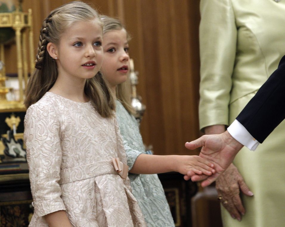 Spain’s new King Felipe VI, wearing the Sash of Captain-General, touches the hand of his daughter Princess Sofia as she stands next to Princess Leonor during a ceremony at La Zarzuela Palace in Madrid
