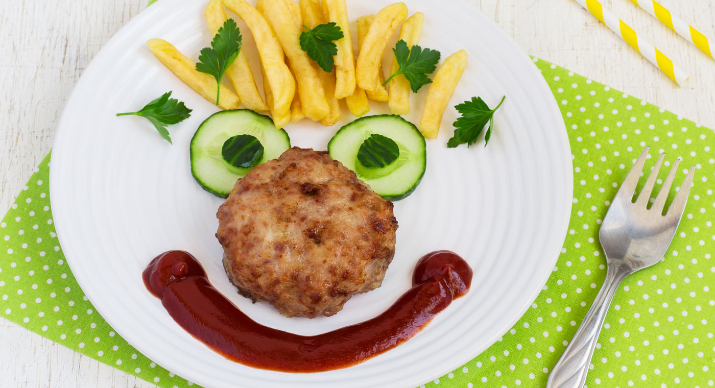 Funny food face with a chop, French fries and cucumber