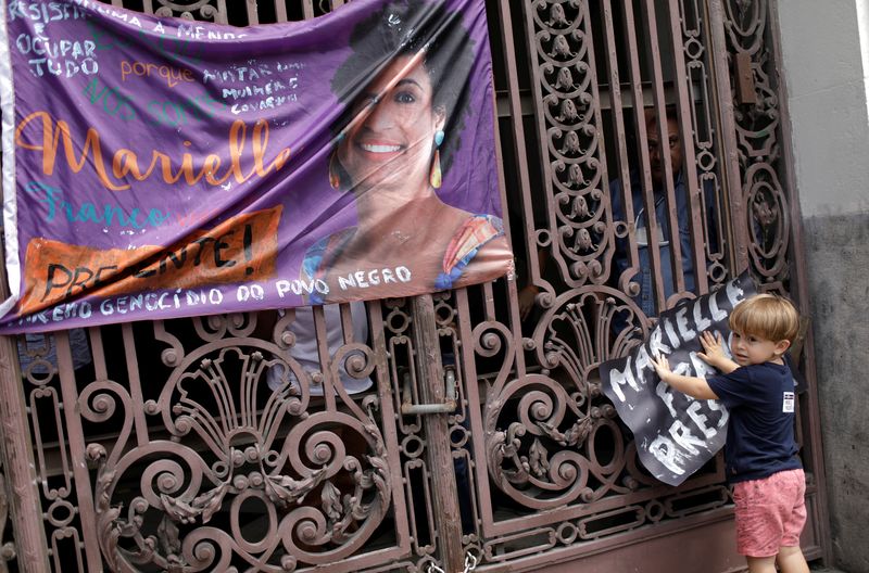 A boy holds a banner next to a picture of the Rio de Janeiro city councillor Marielle Franco, 38, who was shot dead, during a demonstration ahead of her wake outside the city council chamber in Rio de Janeiro