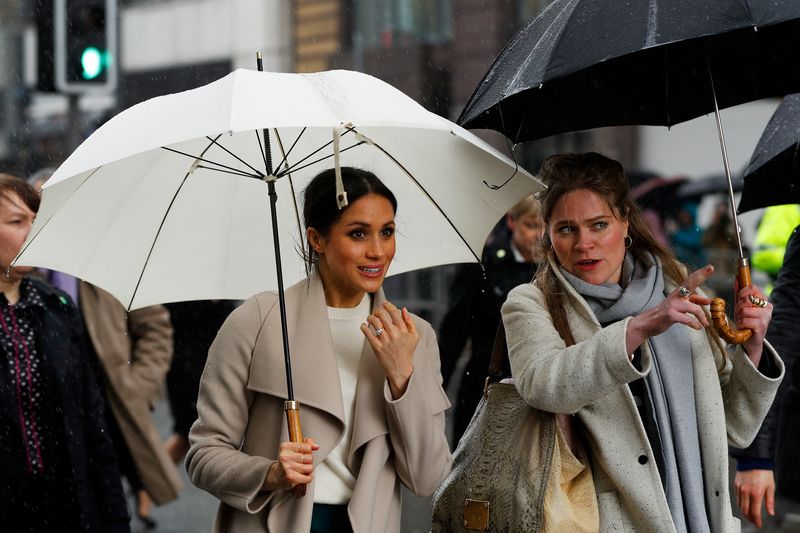 The fiancee of Britain’s Prince Harry, Meghan Markle, shelters under an umbrella after visiting the Crown Bar in Belfast