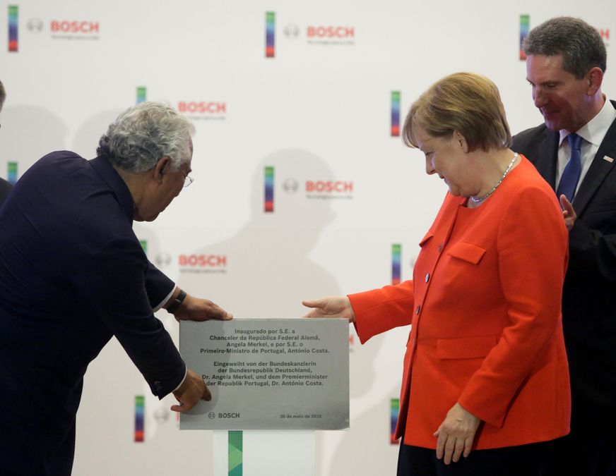 German Chancellor Angela Merkel uncovers a commemorative plaque at a Bosch developing center during a two-day official visit in Braga