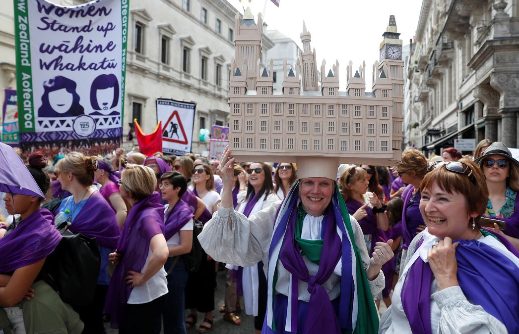 A woman wears a hat shaped like the Palace of Westminster and clothes in the suffragette colours of green, white and violet – standing for Give Women Votes – as she marches in the ‘Processions’ women’s march in London
