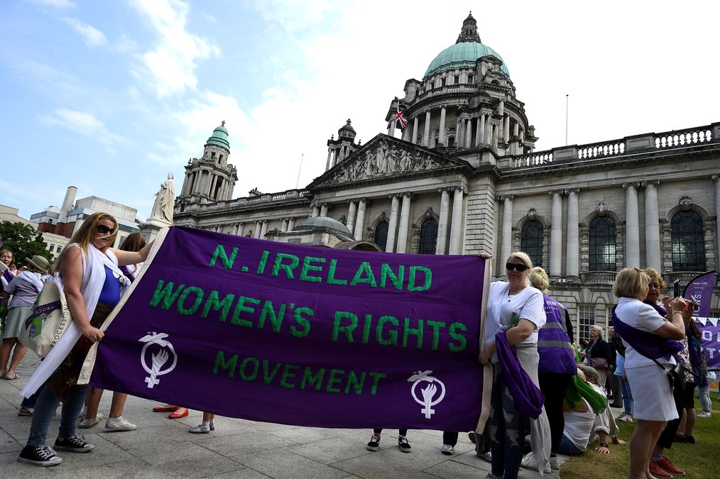 Women hold a banner decorated with the suffragette colours of green, white and violet – standing for Give Women Votes – as she marches in the ‘Processions’ women’s march in Belfast
