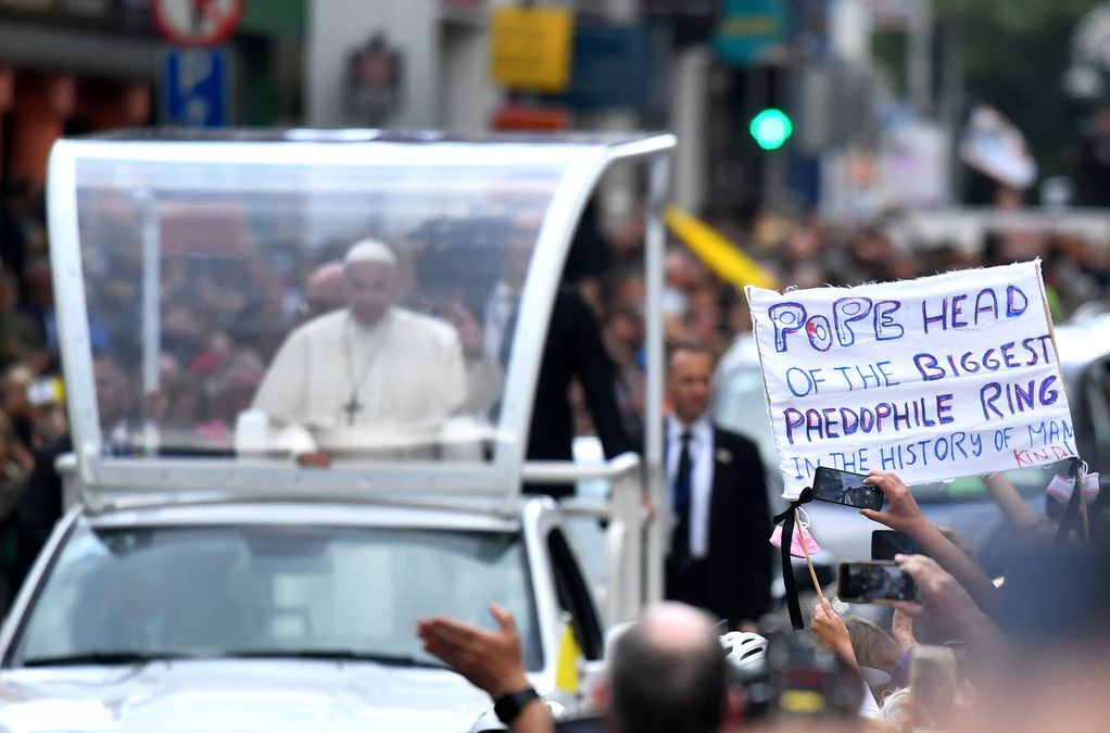 A protestor holds a banner as Pope Francis drives by during his visit in Dublin